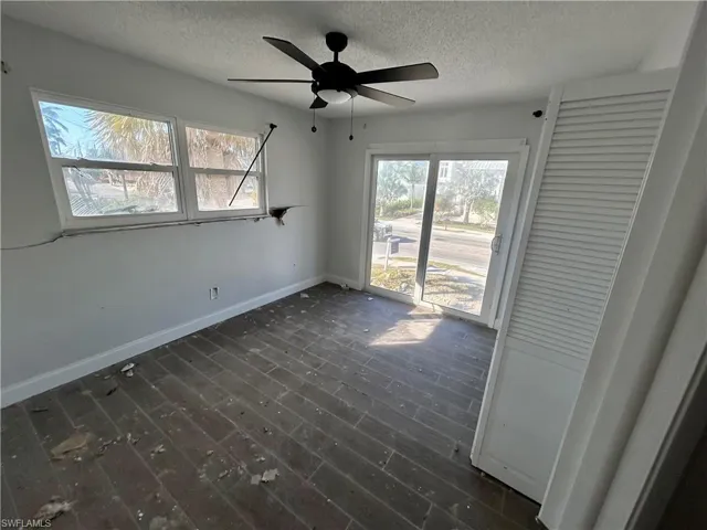 Empty room with a textured ceiling, ceiling fan, and dark hardwood / wood-style floors