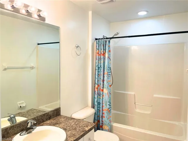 Bathroom featuring shower / bath combo with shower curtain, vanity, and recessed lighting