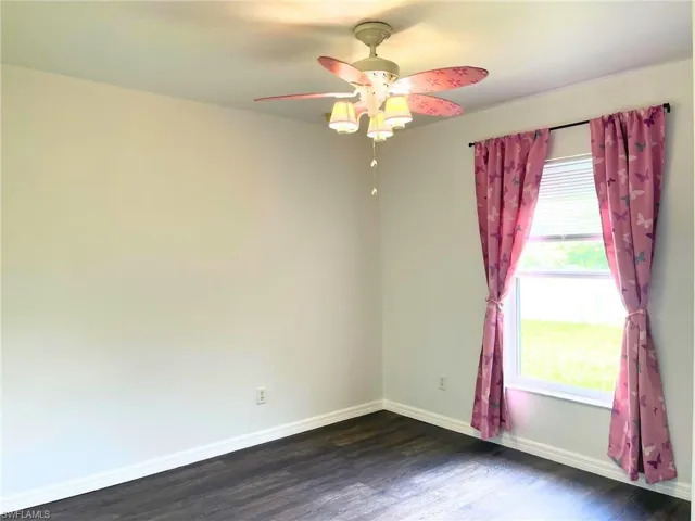 Spare room featuring dark wood-style flooring and a ceiling fan