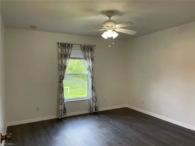 Spare room with dark wood-type flooring, a ceiling fan, and a smoke detector