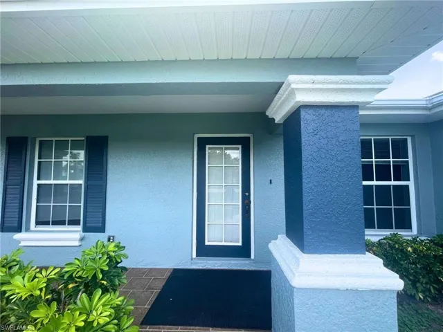 Entrance to property with stucco siding and covered porch