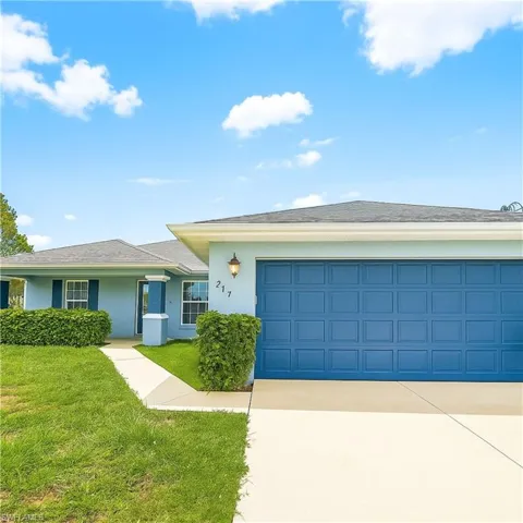 Ranch-style home with an attached garage, driveway, a front yard, and stucco siding
