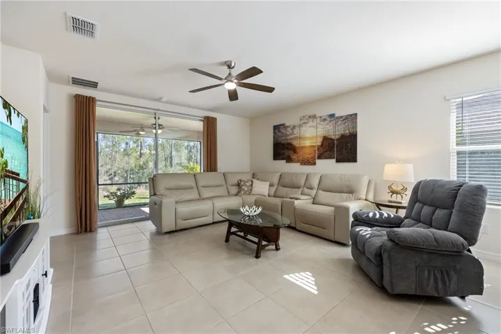 Living area featuring lit ceiling fan and tile floors