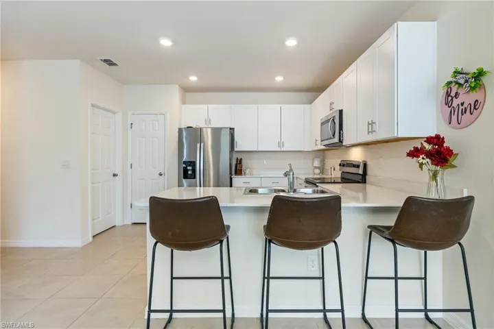 Kitchen featuring appliances with stainless steel finishes, white cabinets, a peninsula, a breakfast bar area, and recessed lighting
