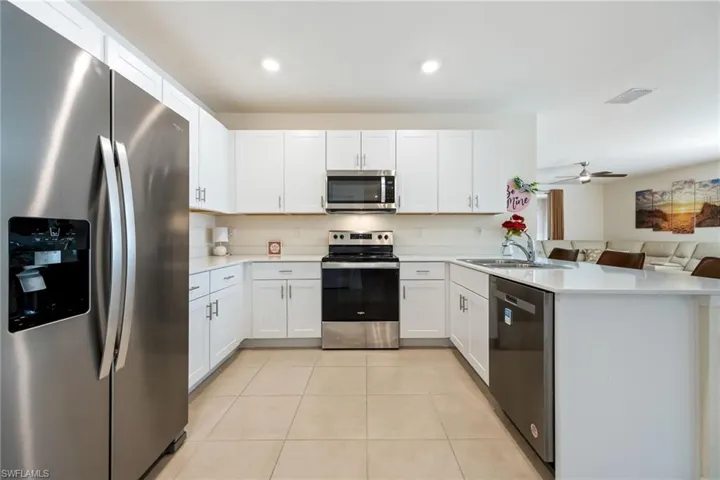 Kitchen with stainless steel appliances, white cabinets, a peninsula, and ceiling fan