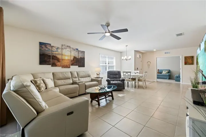 Living area featuring lit ceiling fan and tile floors
