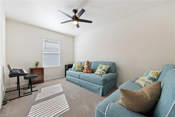 Den with carpet flooring and a lit ceiling fan