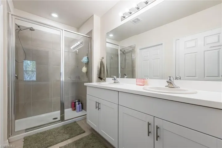 Full bath featuring double vanity and a stall shower