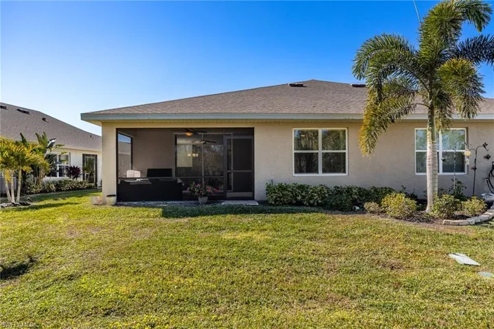 Rear view of house with a lawn and screened lanai