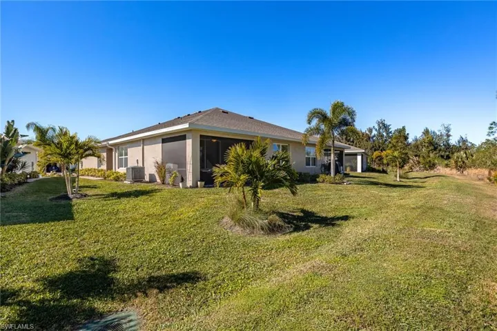 Rear view of house with a lawn and screened lanai