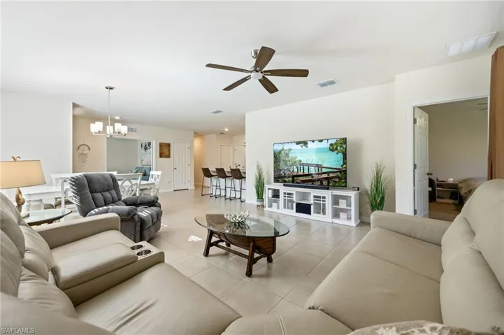 Living area featuring lit ceiling fan and tile floors