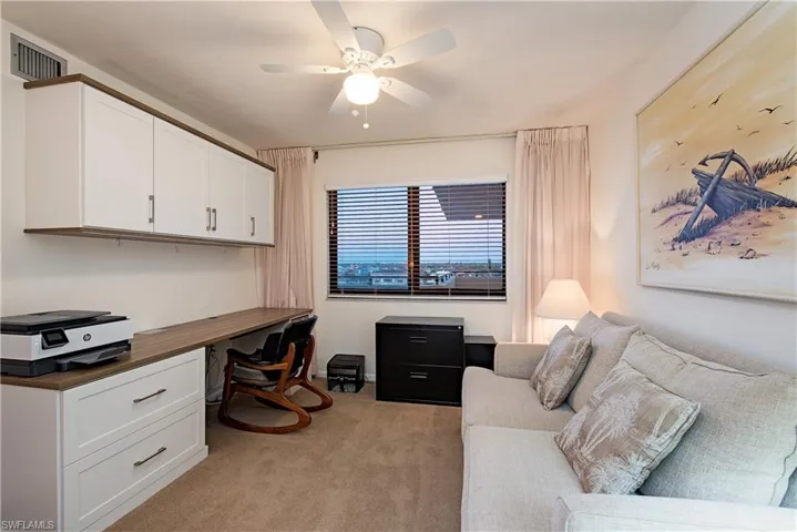Carpeted office space with ceiling fan and built in desk