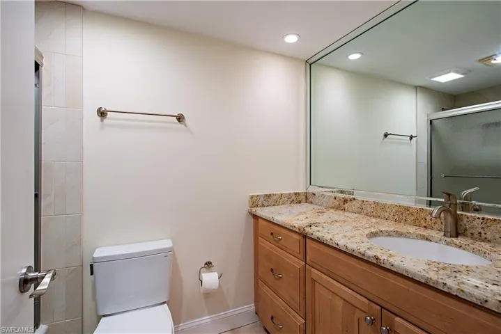 Bathroom with an enclosed shower, vanity, and toilet