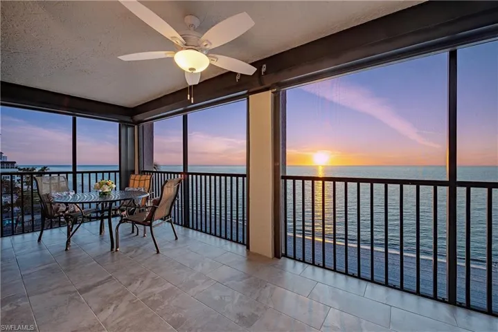 Sunroom with ceiling fan and a water view