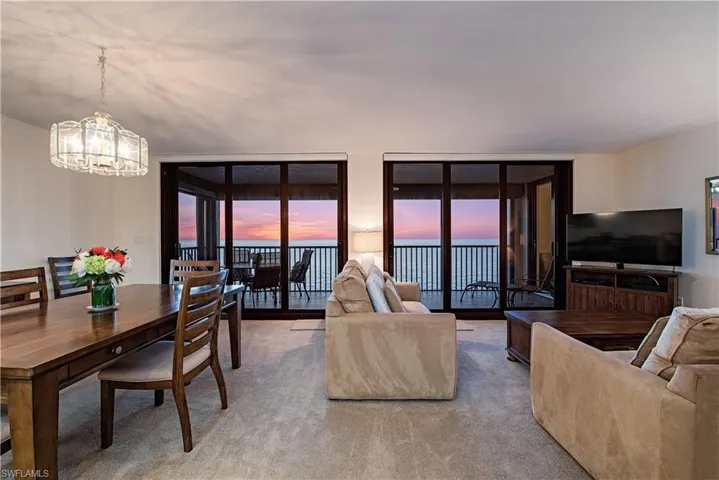 Living room with floor to ceiling windows, carpet floors, and a chandelier