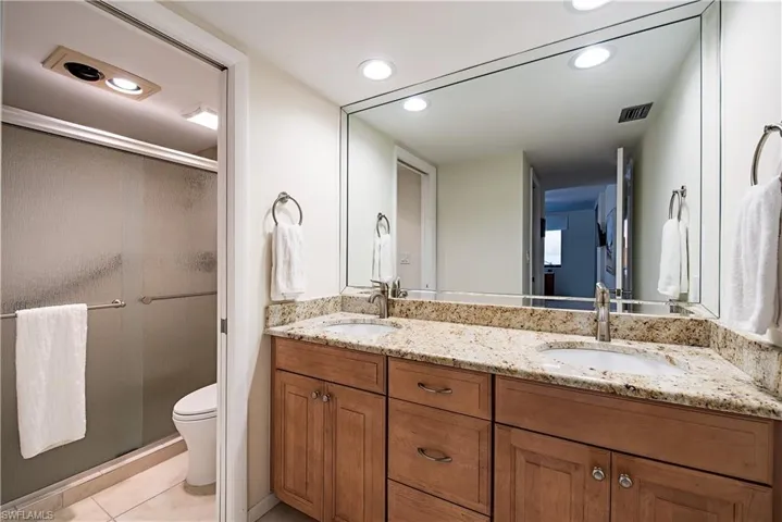 Bathroom with tile patterned flooring, vanity, toilet, and a shower with shower door