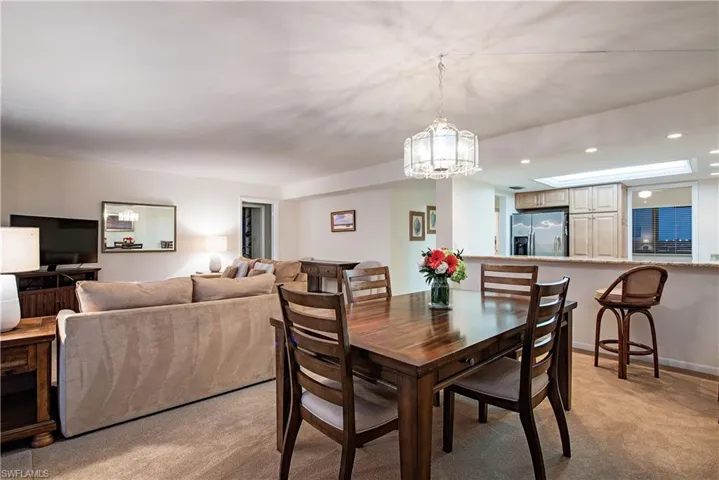 Dining area with light carpet and an inviting chandelier
