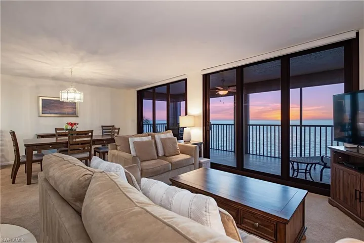 Living room featuring floor to ceiling windows, light carpet, and a chandelier