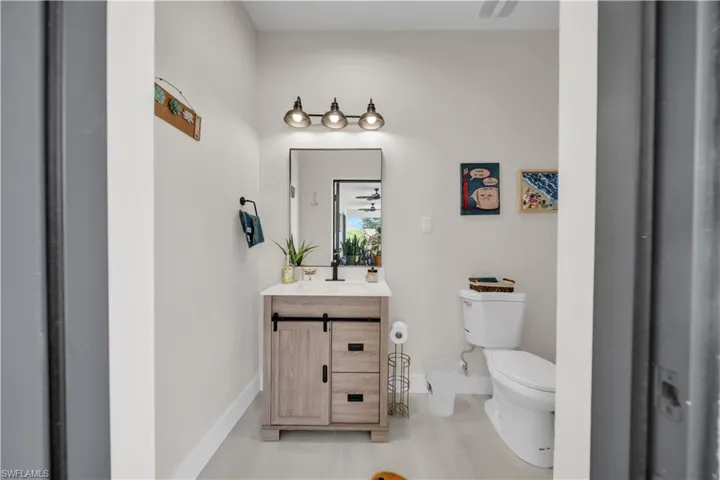 Bathroom featuring a light wood-finish vanity with a white countertop and rectangular sink, black faucet, and a rectangular mirror