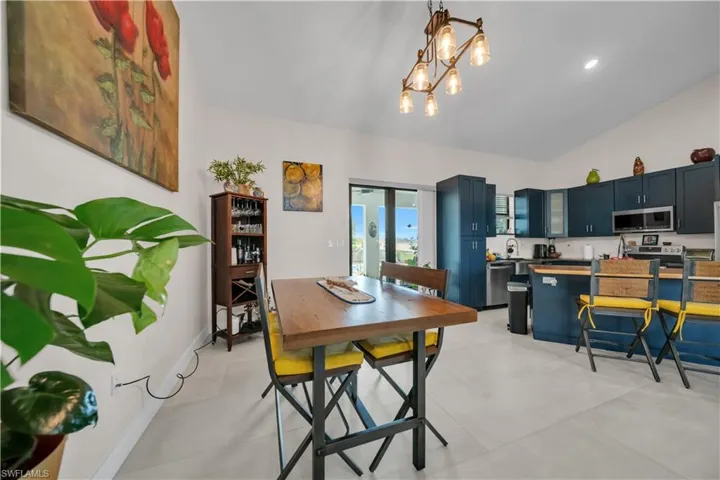 Open-concept kitchen and dining area featuring vaulted ceilings and light-toned tile flooring