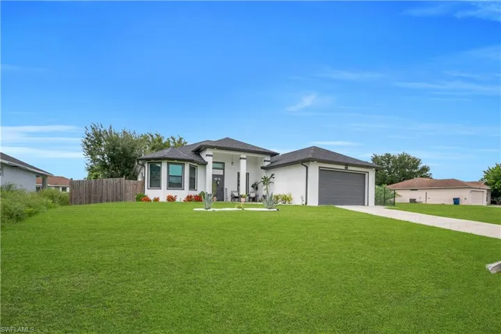 Modern white stucco exterior with a dark gray garage door and a covered front entry