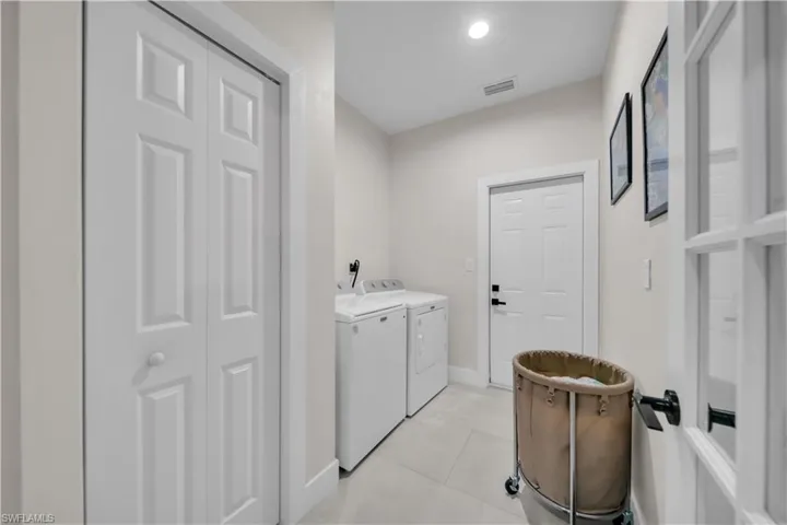 Utility space featuring bi-fold panel doors, a panel entry door with black hardware, and light-toned floor tiling