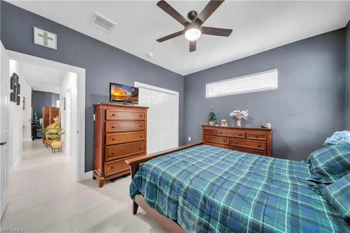 Bedroom featuring light-toned tile flooring, a ceiling fan with integrated lighting, and a horizontal window with blinds