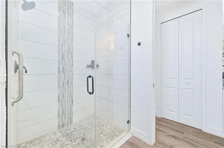 Full bath with a closet, wood finished floors, and a shower stall