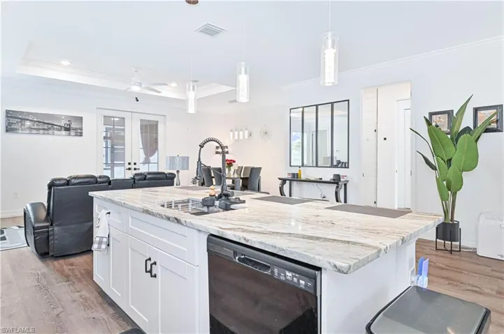 Kitchen featuring ornamental molding, dishwasher, light wood-type flooring, white cabinets, and open floor plan