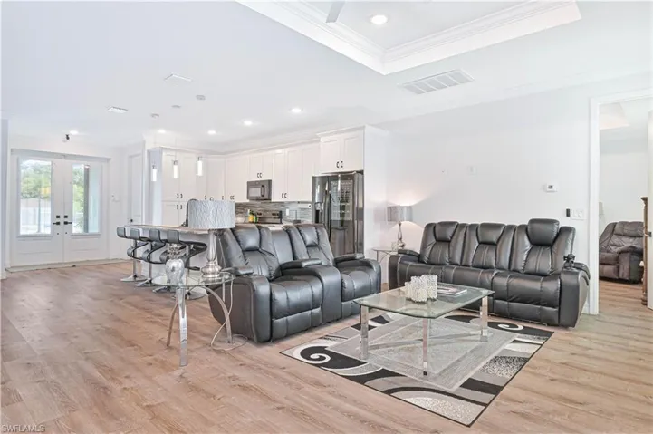 Living room with crown molding, light wood-type flooring, french doors, and recessed lighting