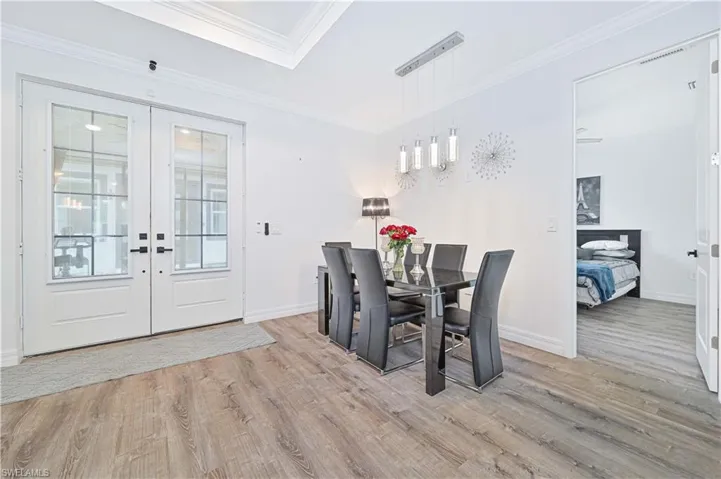 Dining area with wood finished floors, french doors, and crown molding