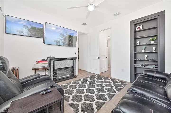 Living room with light wood-type flooring, ceiling fan, and built in features