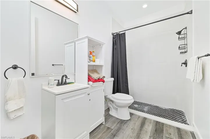 Full bath featuring vanity, wood finished floors, and a tile shower
