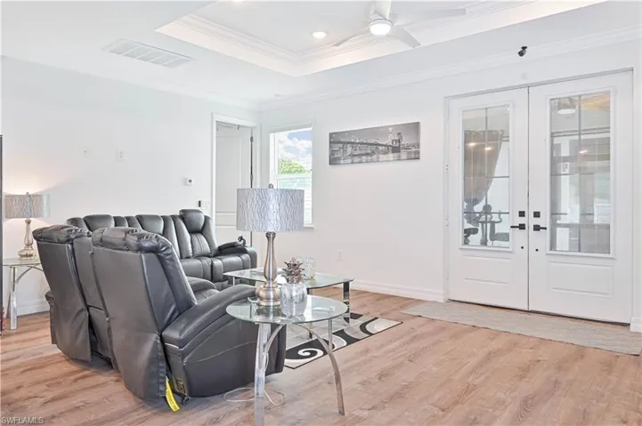 Living area with french doors, light wood-type flooring, ceiling fan, and ornamental molding