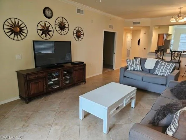 Living area featuring ornamental molding, visible vents, and a notable chandelier