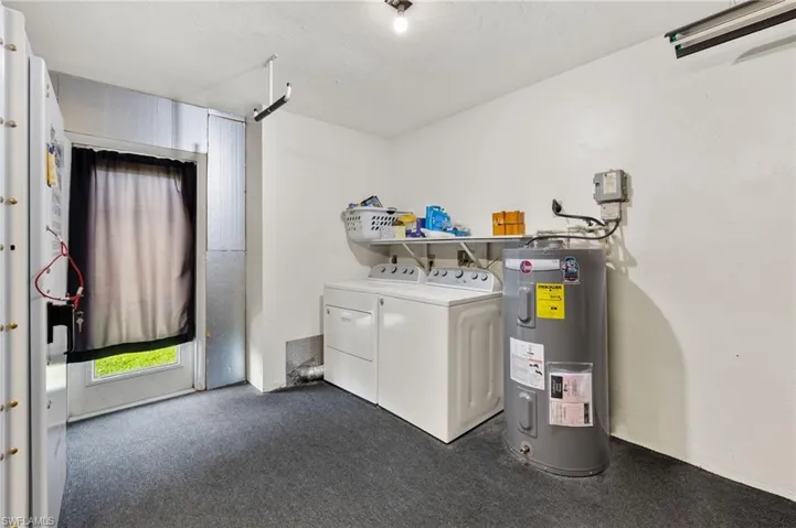 Laundry room featuring washing machine and clothes dryer, water heater, and a barn door