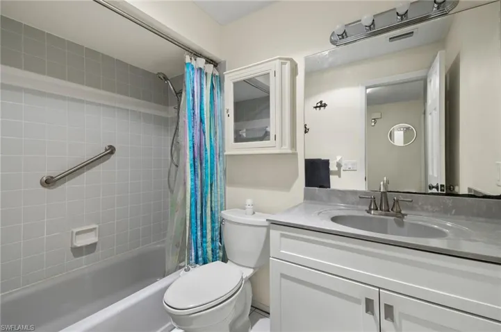 Full bathroom featuring vanity, shower / bath combo with shower curtain, and toilet