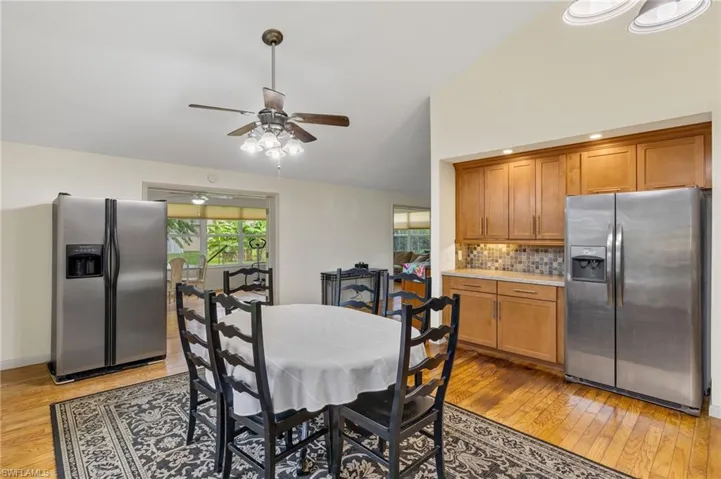 Dining room featuring high vaulted ceiling, ceiling fan, and light wood-type flooring