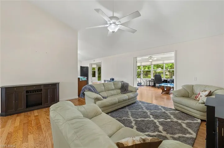 Living room with light hardwood / wood-style floors, ceiling fan, and high vaulted ceiling