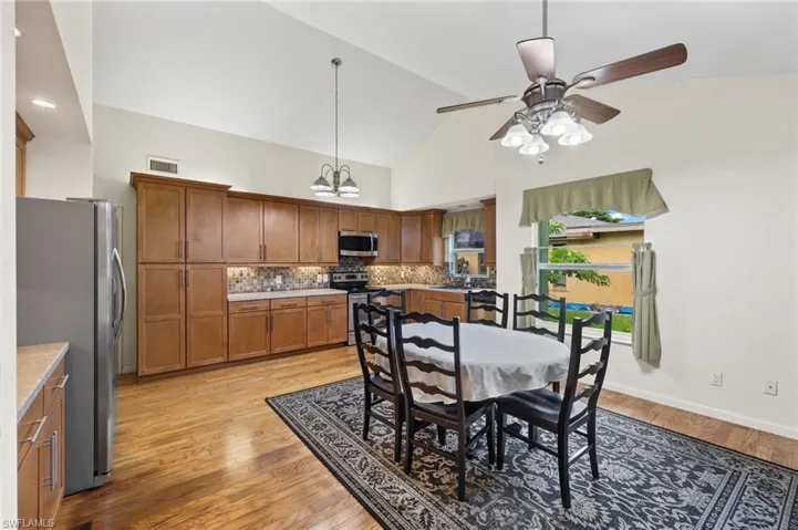 Dining space featuring sink, light hardwood / wood-style flooring, ceiling fan, and high vaulted ceiling
