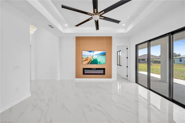 Empty room with a tray ceiling, marble finish floors, recessed lighting, a ceiling fan, and baseboards