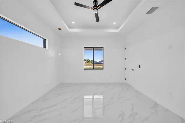 Spare room featuring healthy amount of natural light, ceiling fan, marble finish floors, and recessed lighting