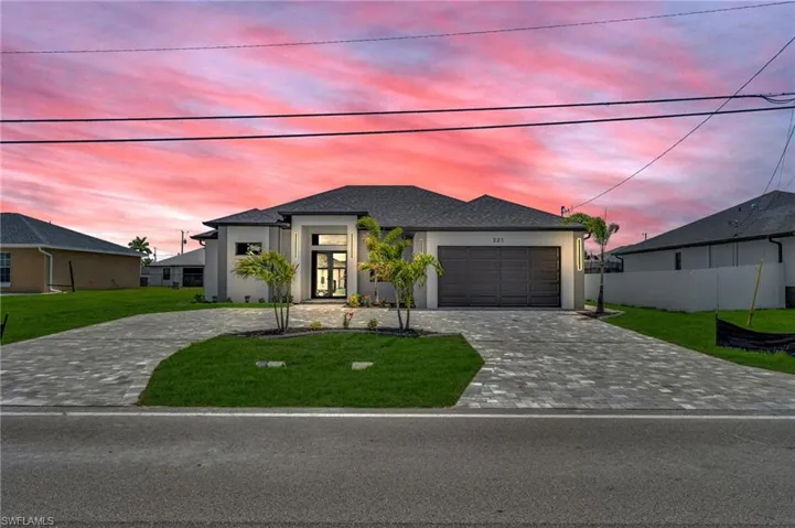 View of front facade featuring decorative driveway, stucco siding, and a garage
