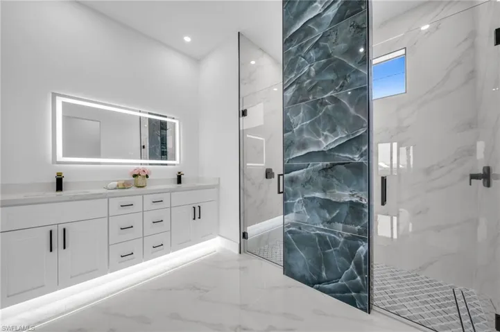 Bathroom with marble tiled flooring, a marble finish shower, and double vanity