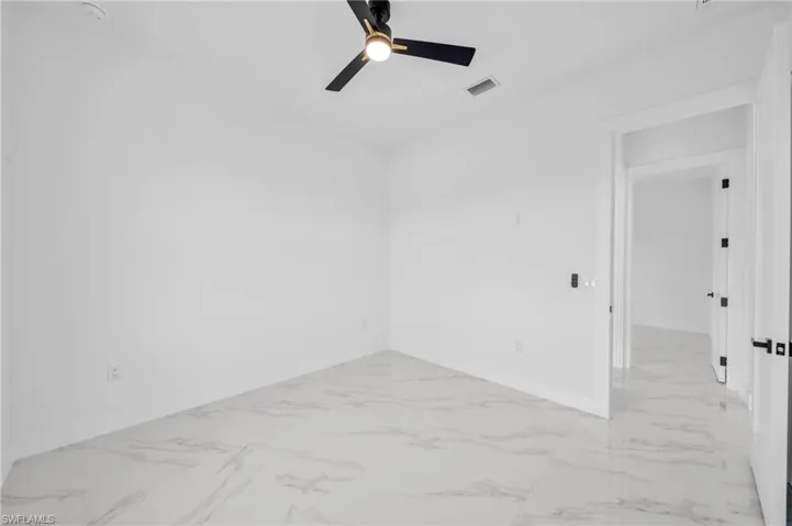 Unfurnished room with light marble finish flooring, ceiling fan, and baseboards