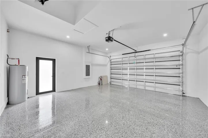 Garage with electric water heater, recessed lighting, a garage door opener, and electric panel