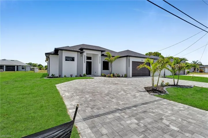 Prairie-style home with decorative driveway, stucco siding, a garage, and a front yard