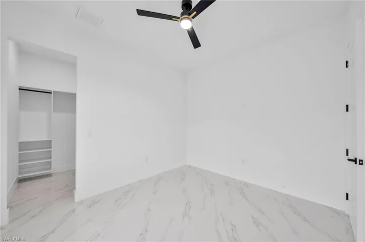 Unfurnished bedroom with marble finish flooring, ceiling fan, and baseboards