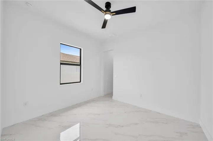 Empty room featuring ceiling fan, marble finish flooring, and baseboards