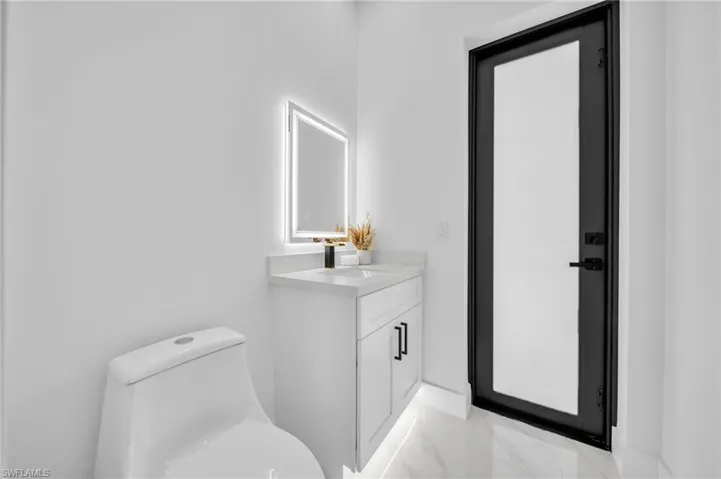 Half bathroom featuring marble look tiles, toilet, and vanity